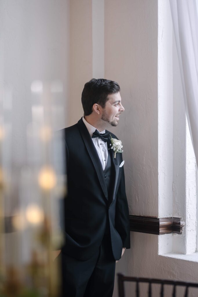 Groom peeking into the courtyard before his wedding ceremony at Casa Marina, Jacksonville Florida