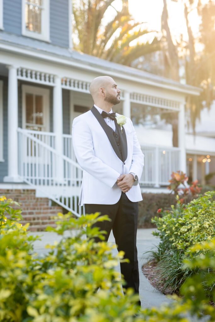 Groom in White and Black Tux Posing at the Highland Manor for Wedding Portraits