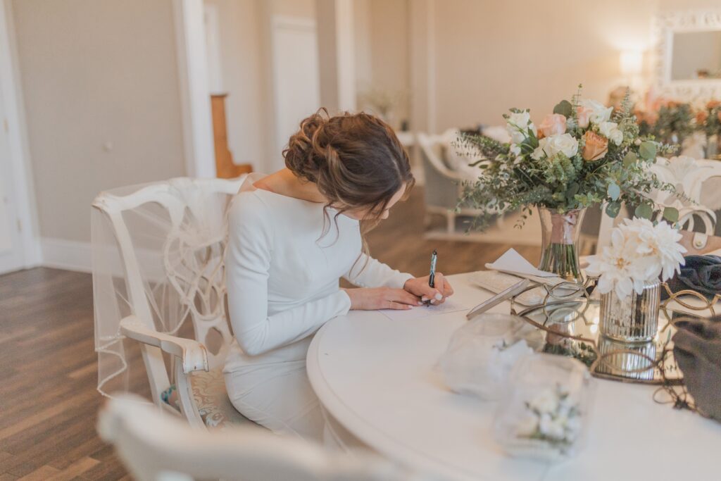 Bride writing a letter to her groom before the ceremony in the bridal suite of The White Room, St. Augustine Florida. Photography by Phavy, Wedding Photographer in St. Augustine.