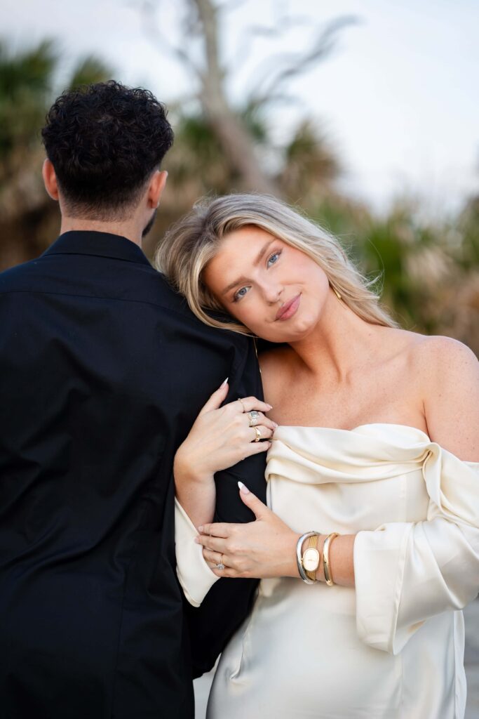 Sunsrise engagement session featuring couple dressed in black and satin white on the shoreline