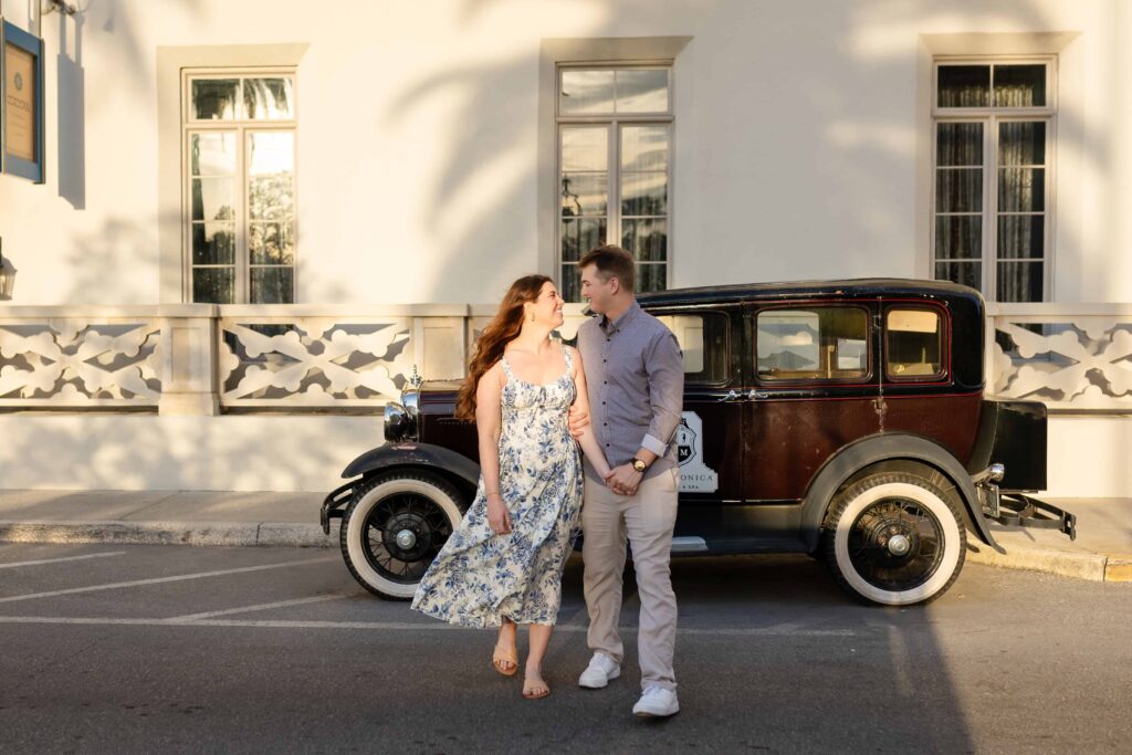 Couple walking hand in hand in front of a vintage car at Casa Monica in St. Augustine
