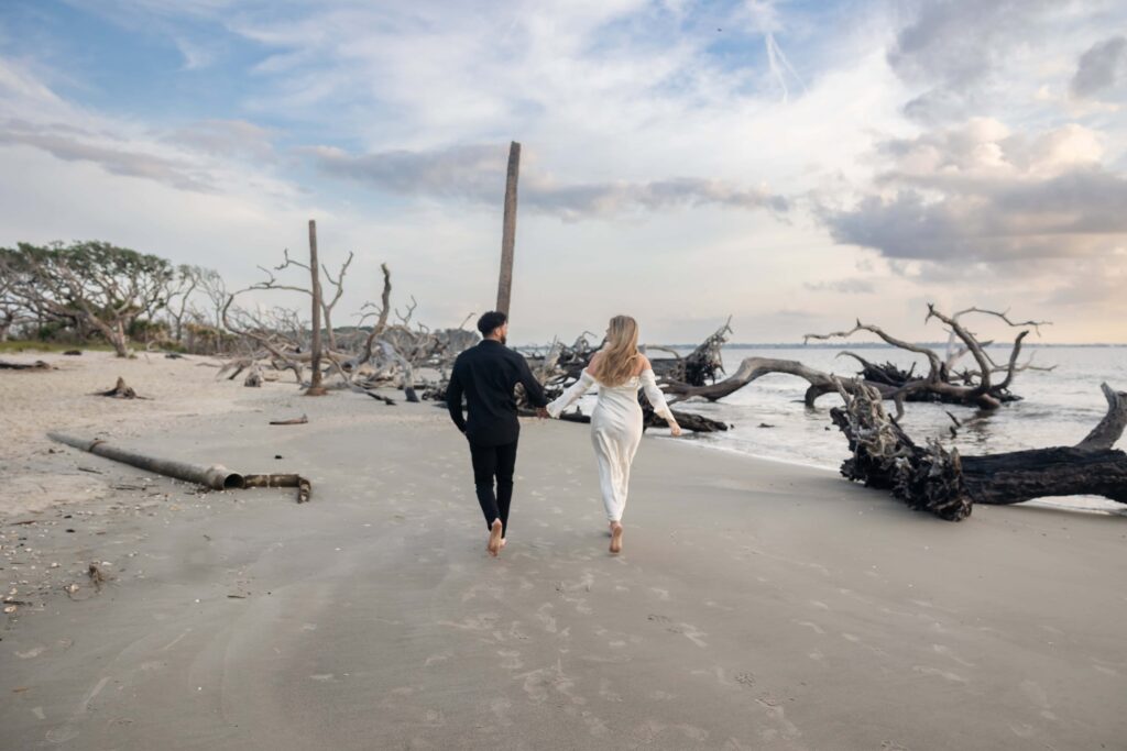 Editorial-style engagement shot on Jekyll Island’s driftwood-filled shore