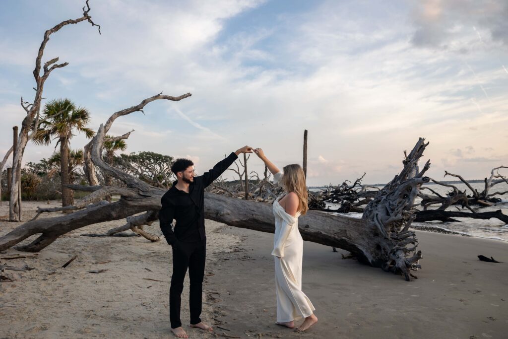 Romantic beach engagement photo with couple twirling during golden hour at Jekyll Island