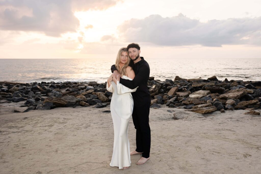 Elegant couple holding each other at the beach during sunset engagement shoot