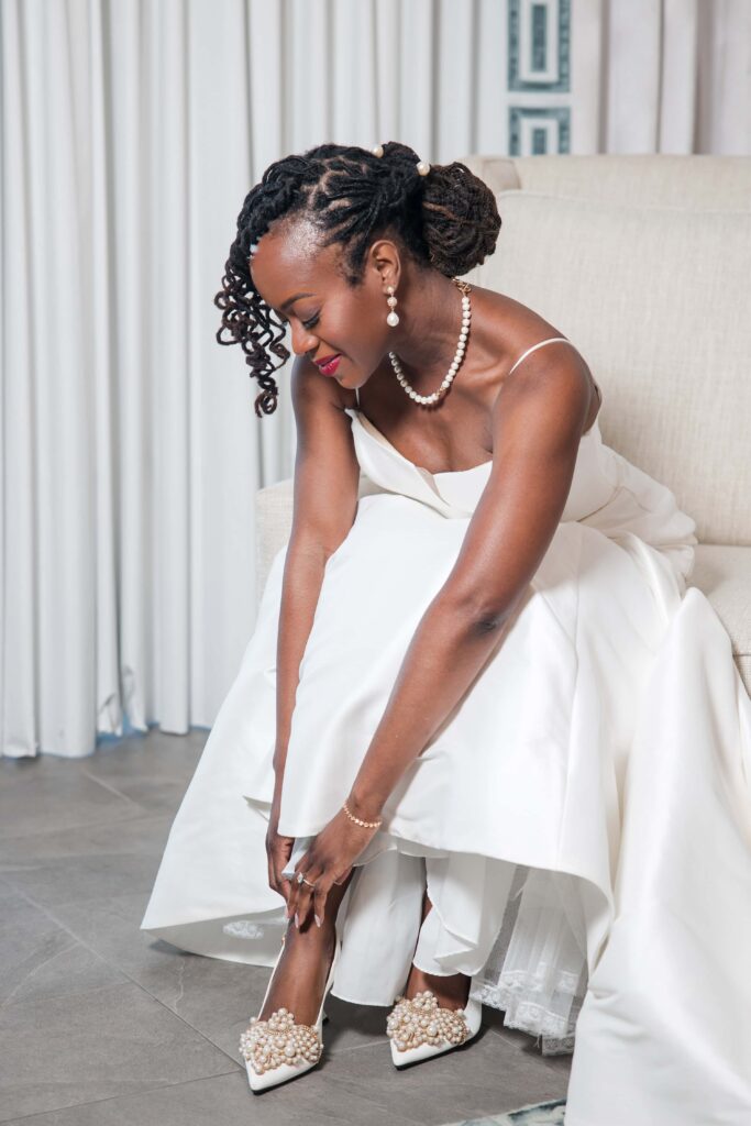Bride putting on pearl-embellished wedding heels at Azaleana Manor in Orange Park, Florida.