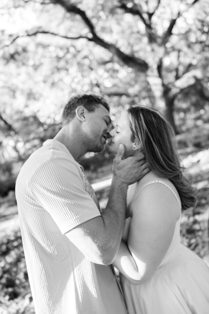 Couple kissing beneath moss-covered oak trees after getting engaged
