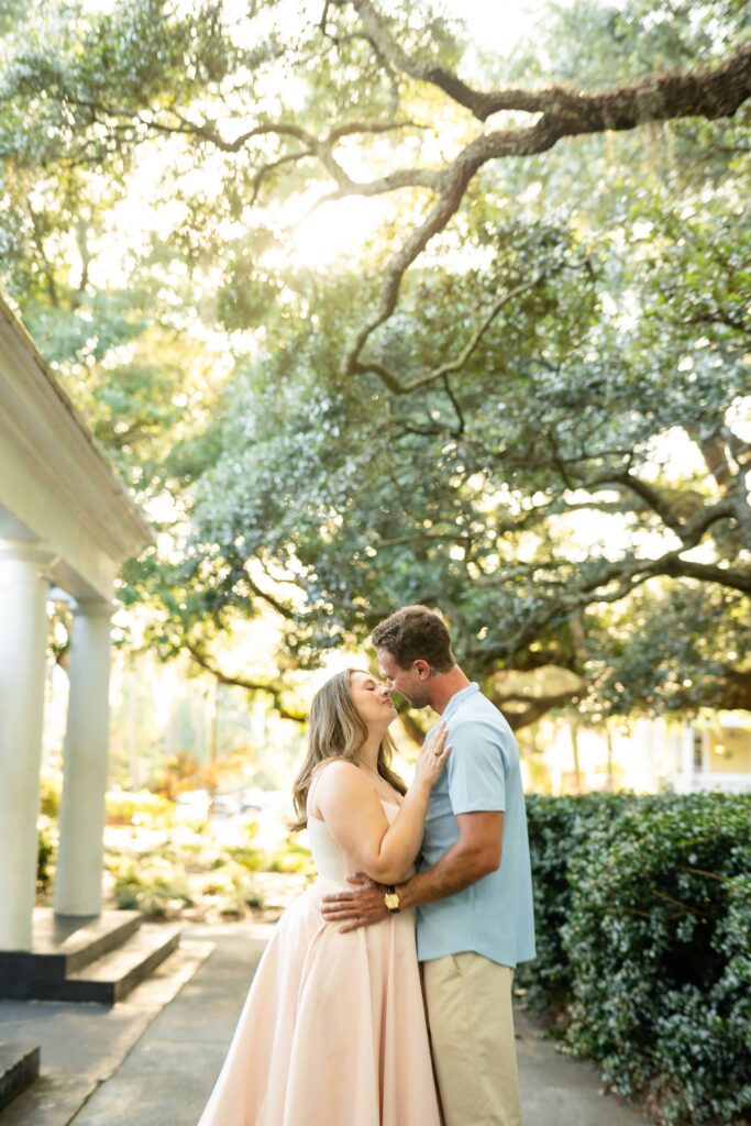 Couple kissing beneath moss-covered oak trees after getting engaged